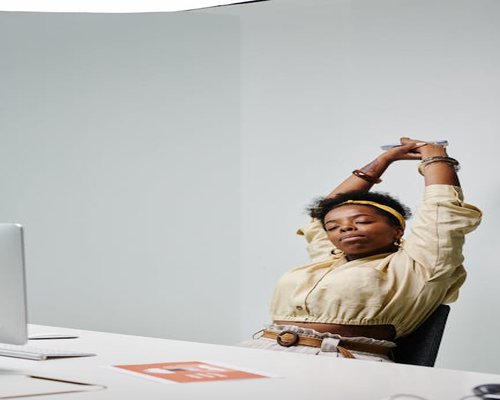 A person stretching gently at their office desk